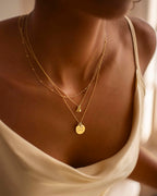 Close-up of a person wearing gold necklaces with a neutral background | Christmas Auntie