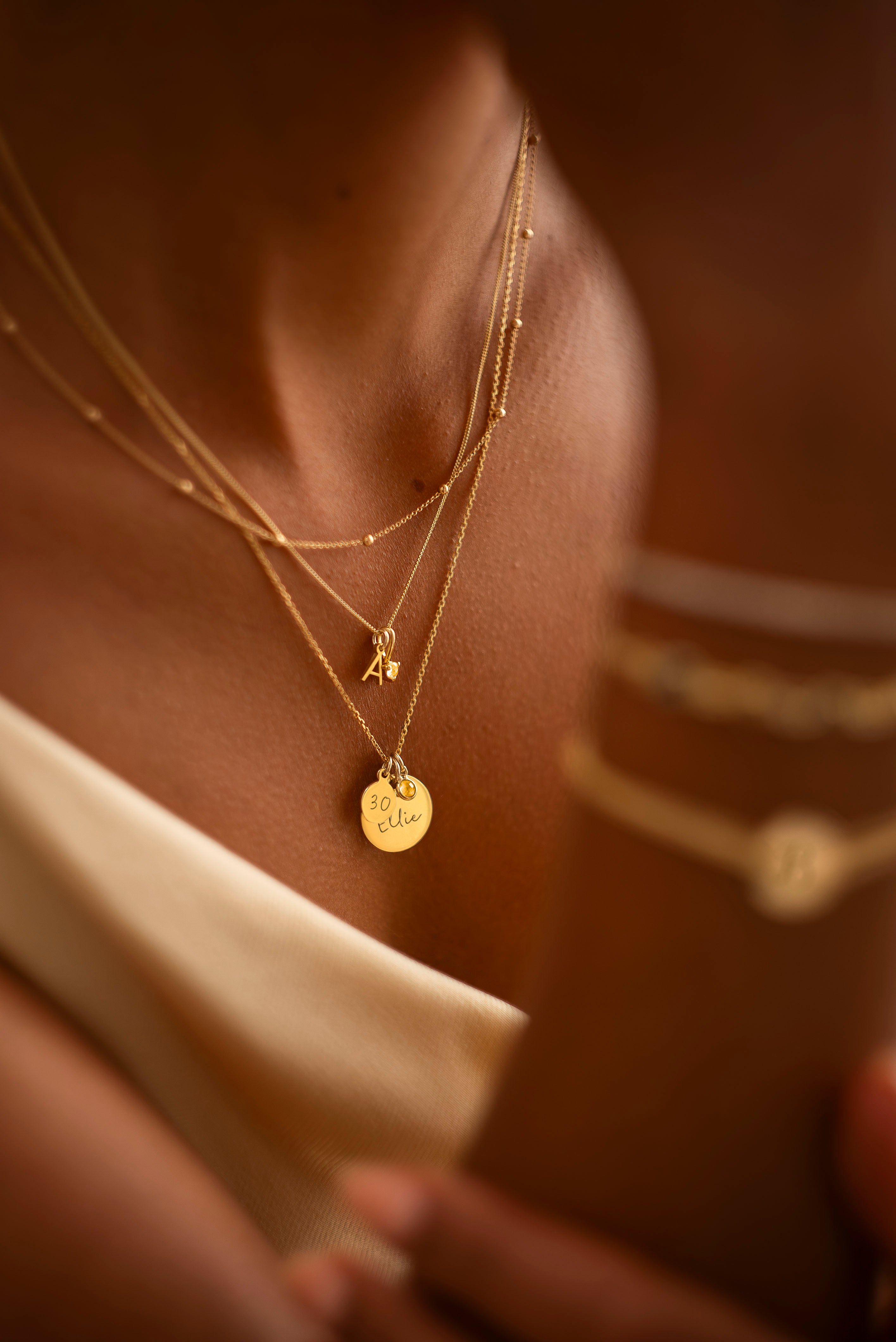 Close-up of a person wearing multiple gold necklaces with visible pendants.