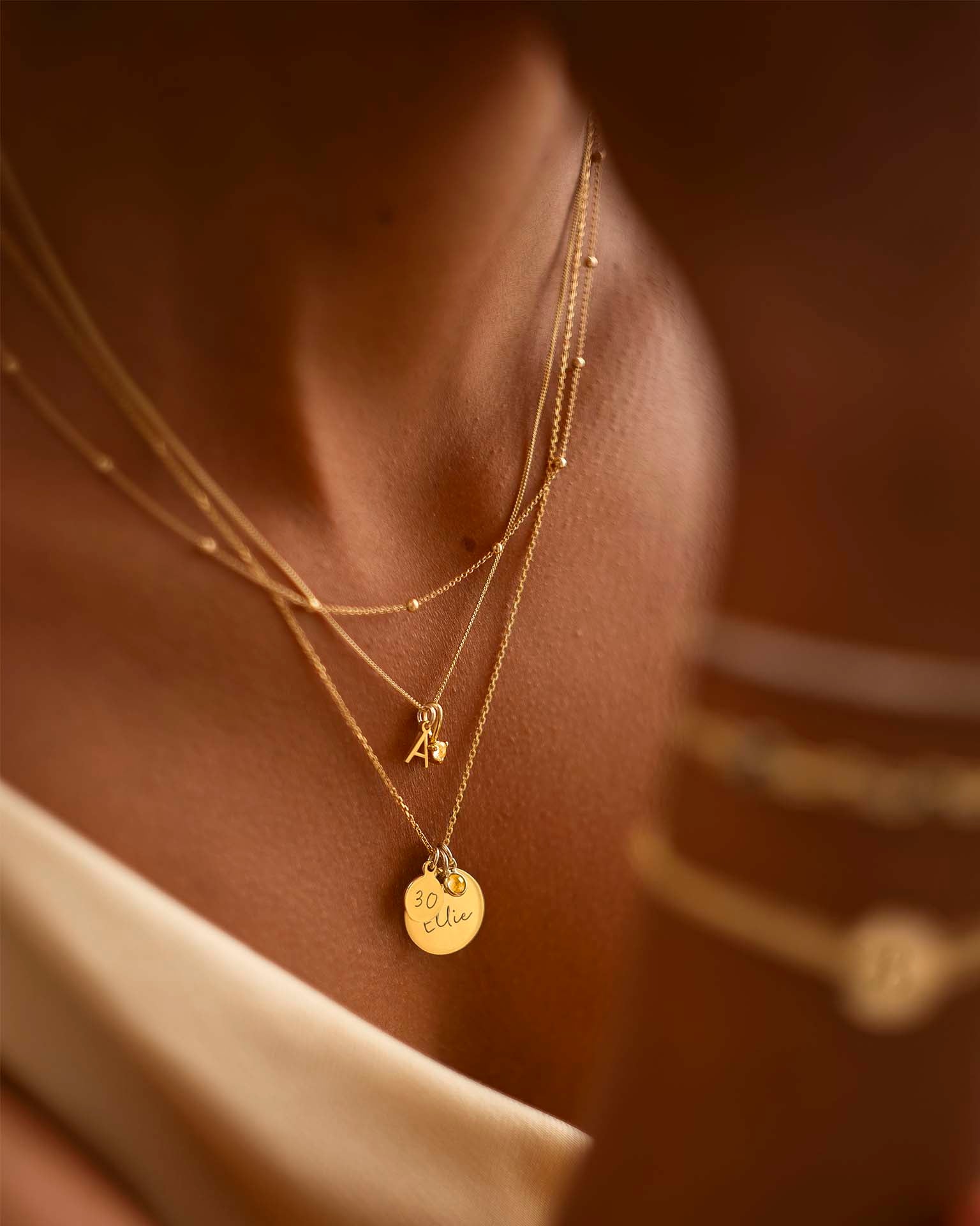 Close-up of a person wearing gold necklaces with visible pendants.