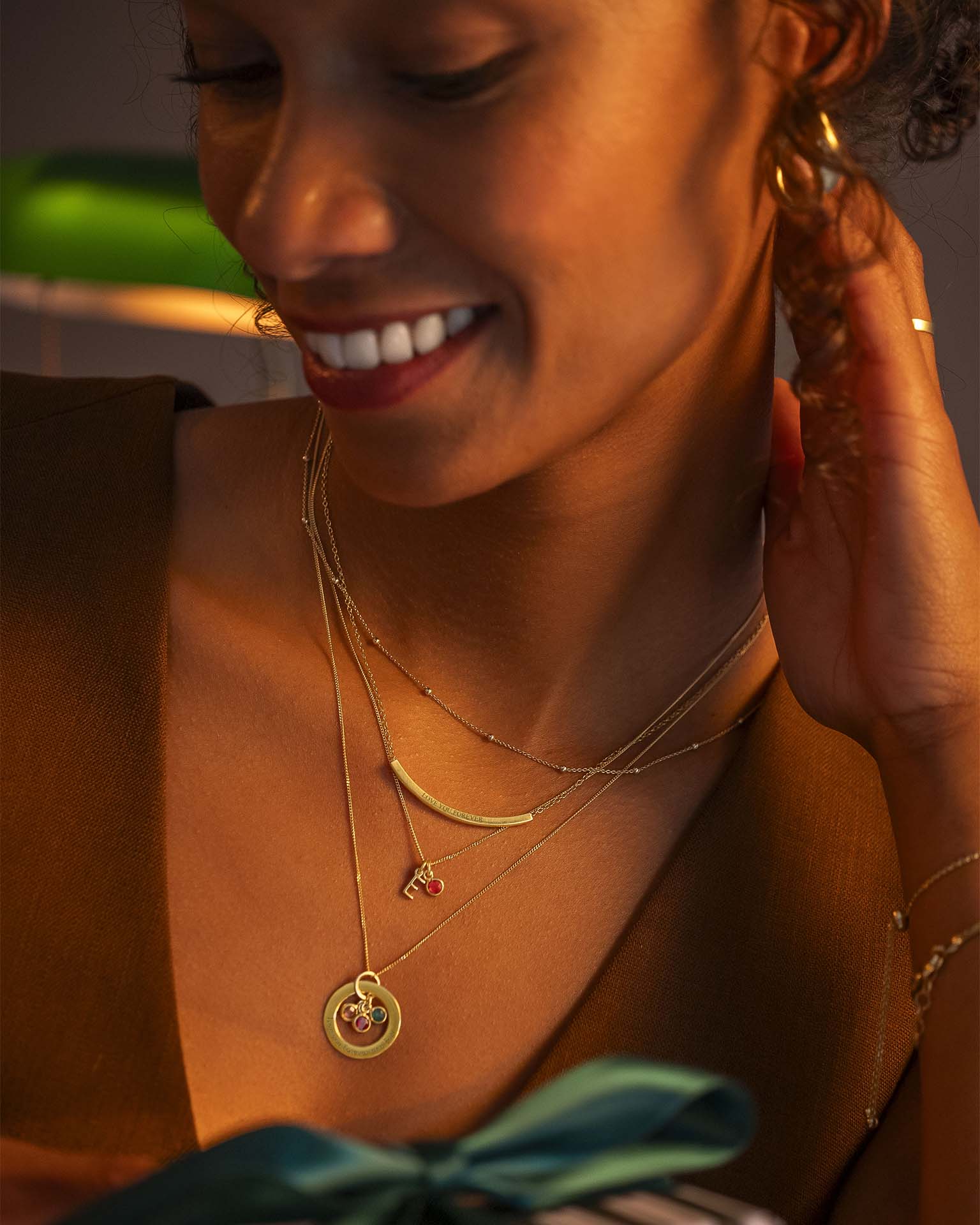 Woman wearing gold jewelry, including earrings and necklaces, with a warm glow.