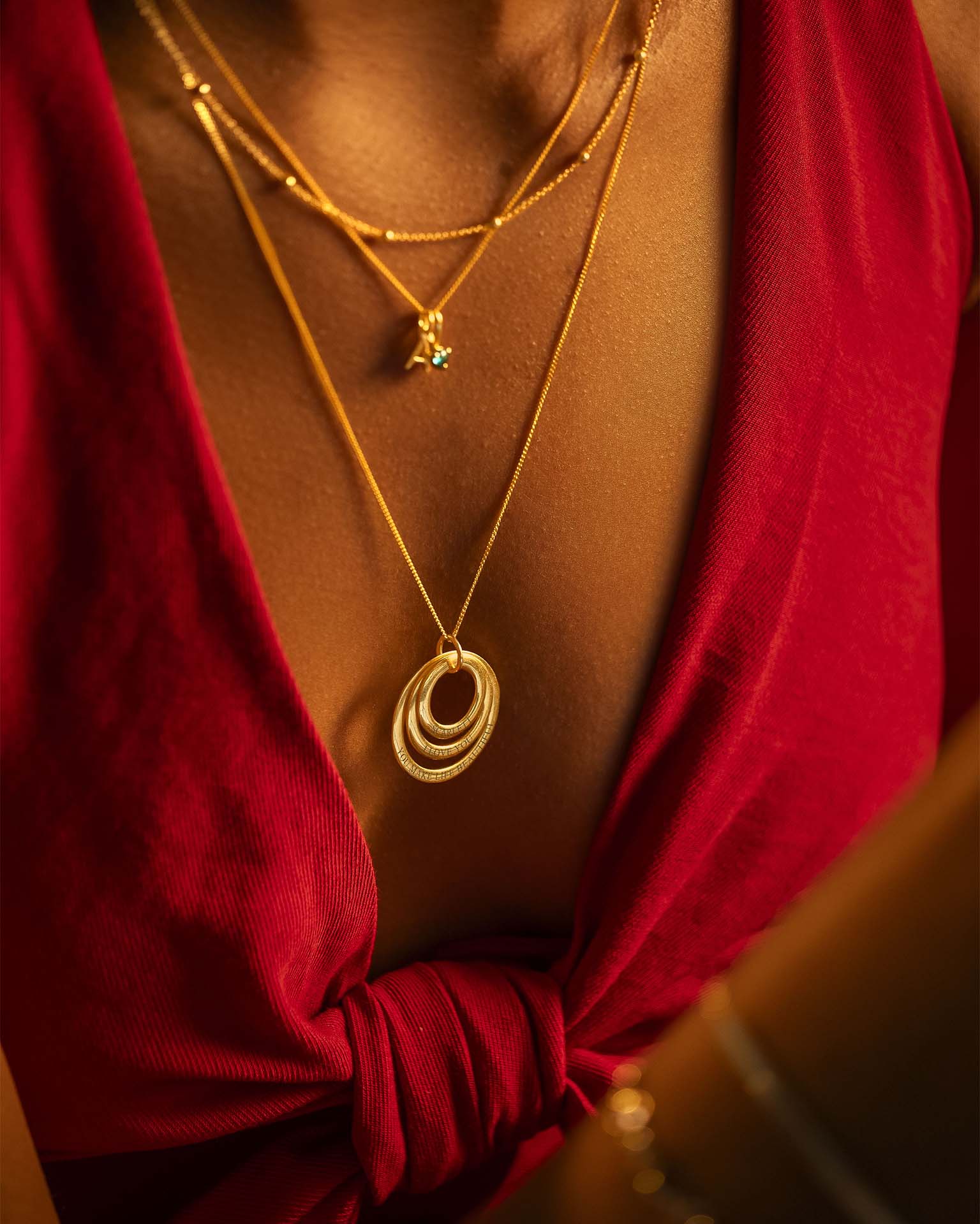Gold necklaces with circular pendants on a red garment