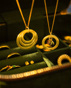 Gold necklaces with circular designs on a green jewelry box