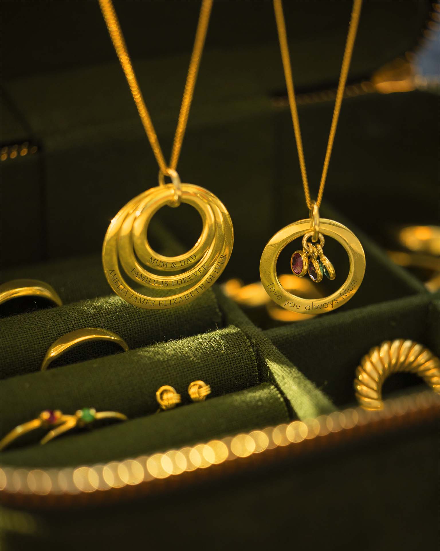 Gold necklaces with circular designs on a green jewelry box