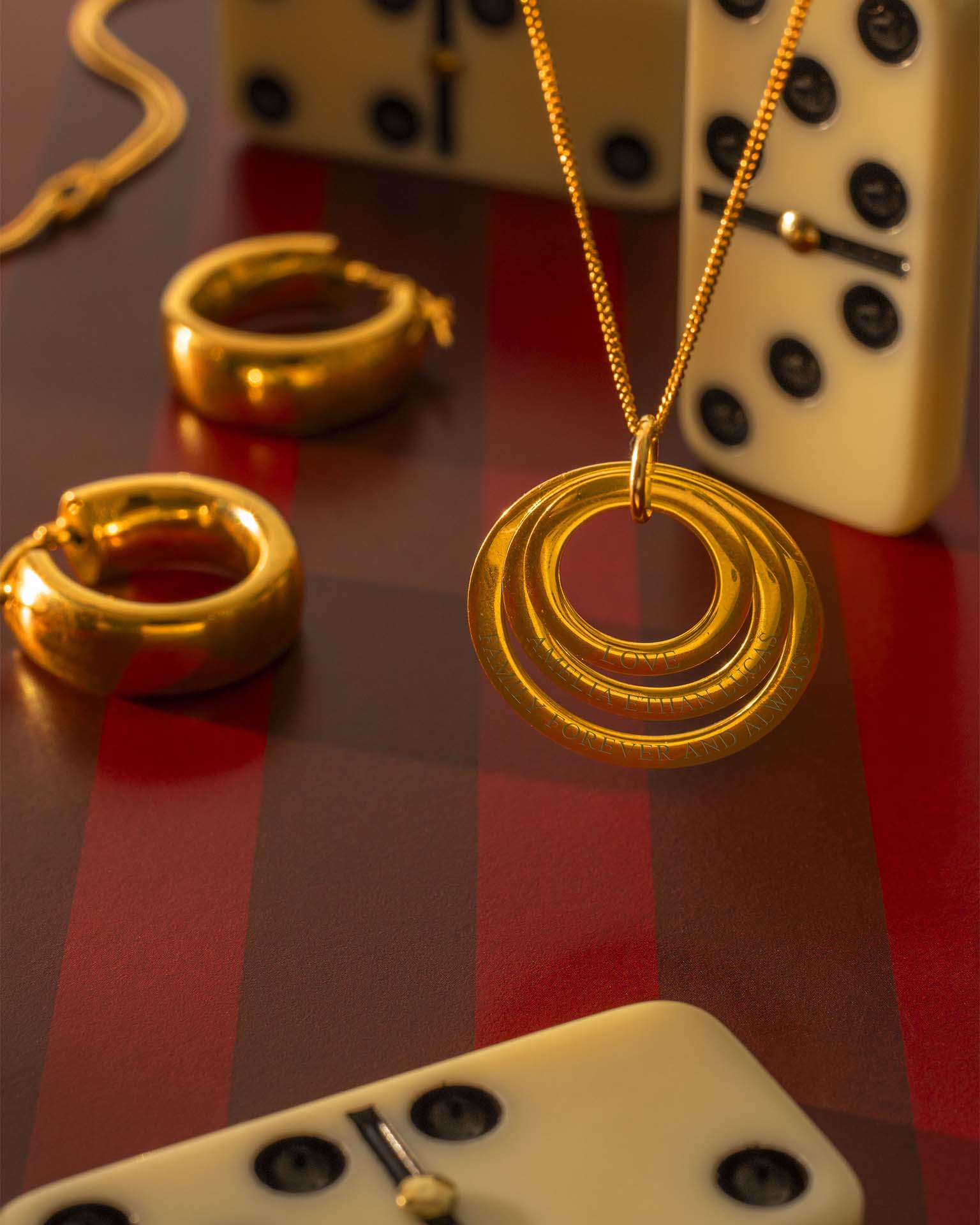 Gold necklace and earrings on a checkered surface with dice in the background
