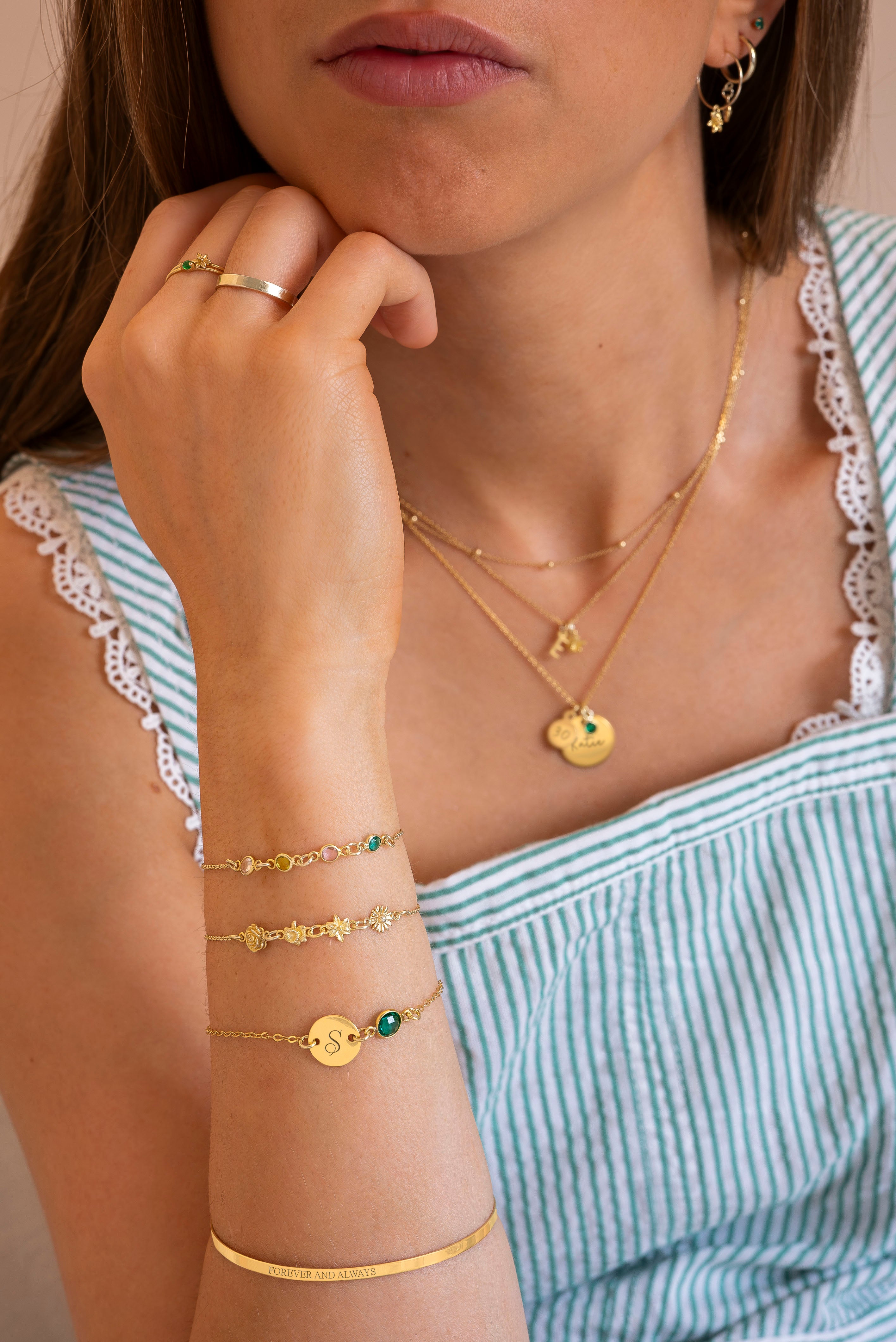 Woman wearing gold jewelry including necklaces, bracelets, and earrings.