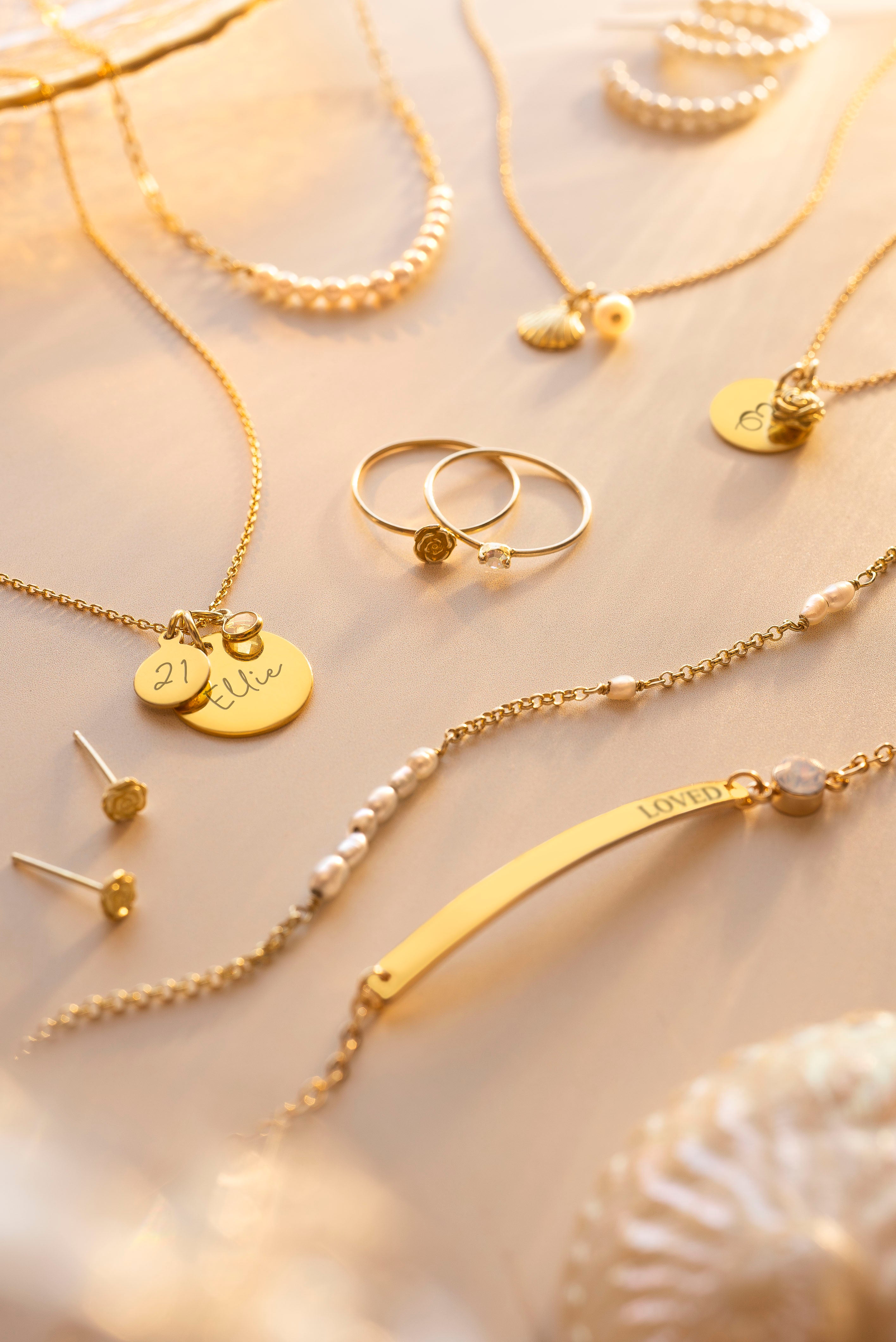 Gold jewelry including necklaces, rings, and earrings on a light background
