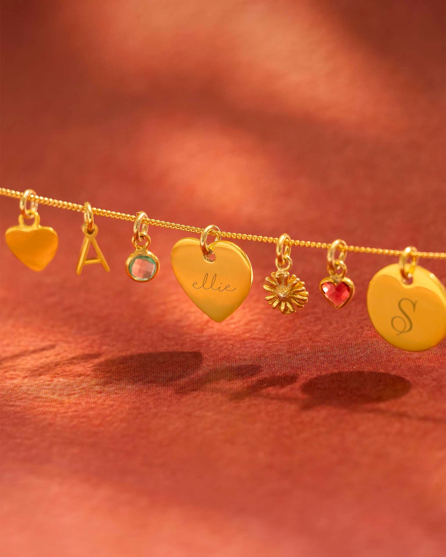 Gold charm bracelet with various charms on a warm brown background