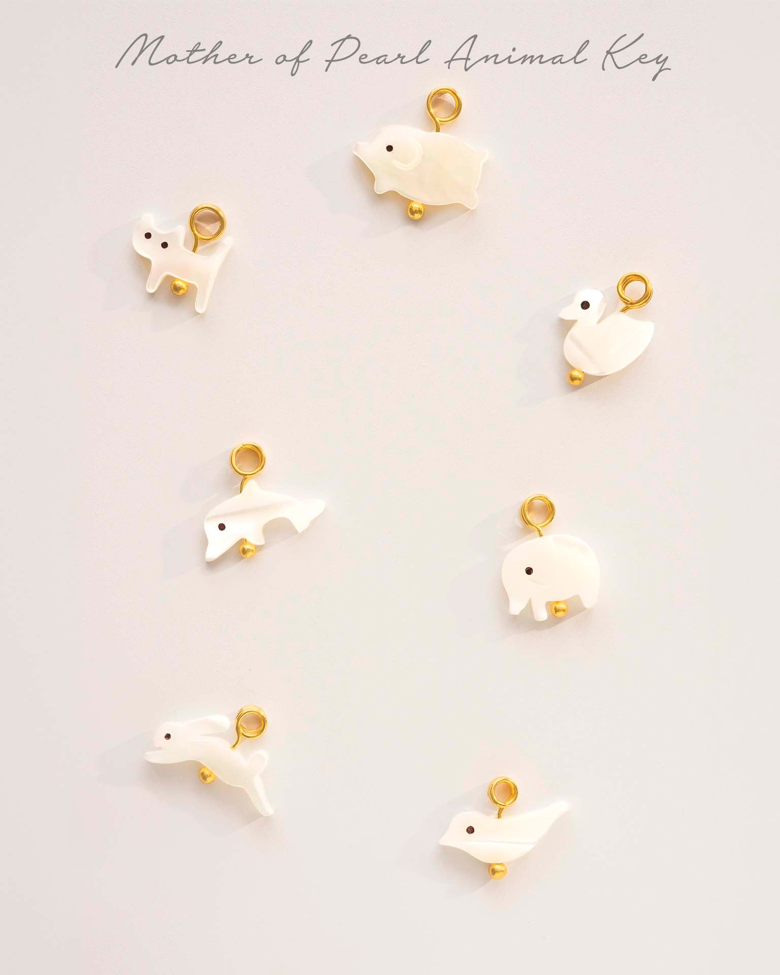 Set of white animal keychains with gold accents on a light gray background