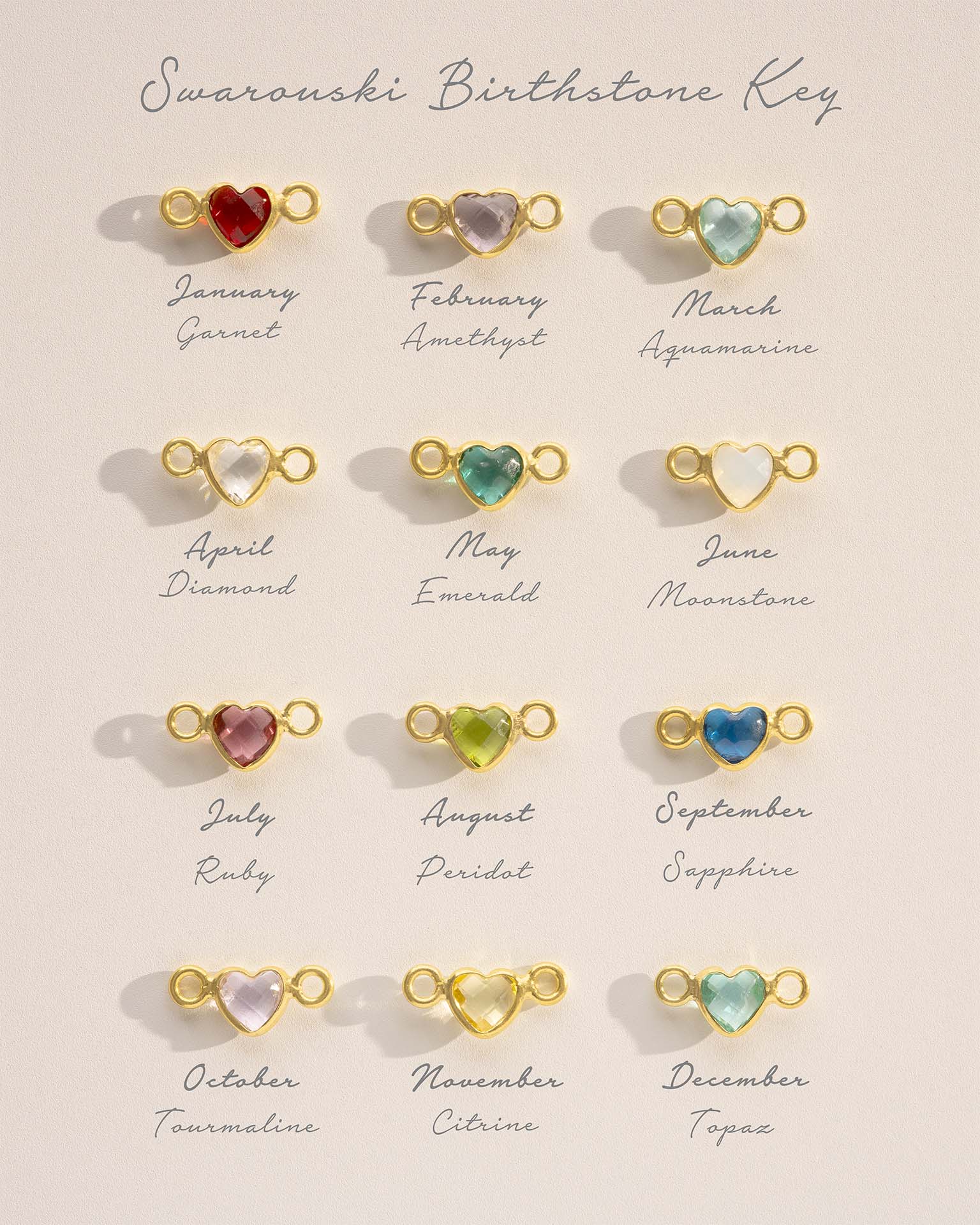 Collection of Swarovski birthstone key pendants on a beige background