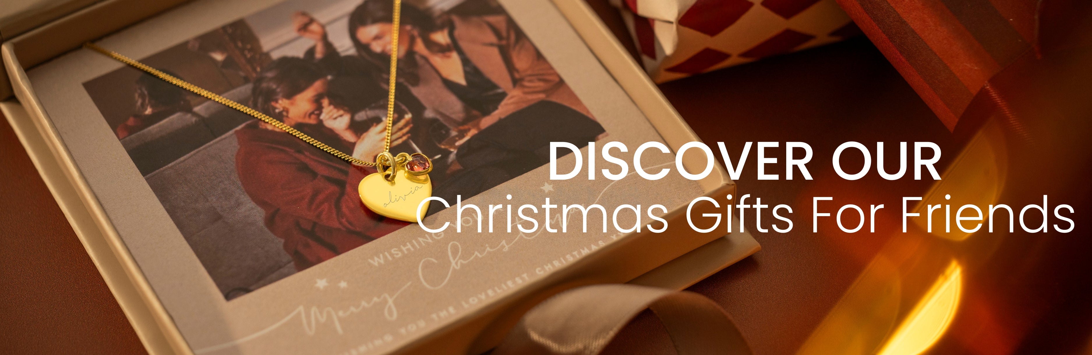 Christmas gift advertisement with a heart-shaped necklace and photo album on a wooden surface.