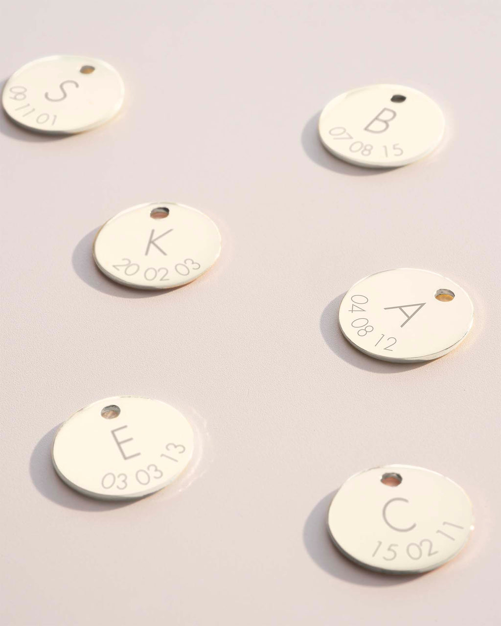 Gold tags with engraved letters and dates on a light gray background