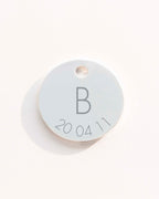 Round light blue tag with letter 'B' and numbers '200411' on a white background