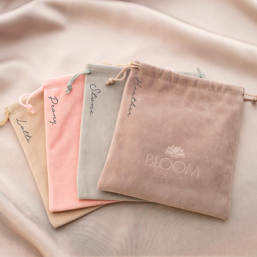 Set of branded velvet pouches on a soft fabric background