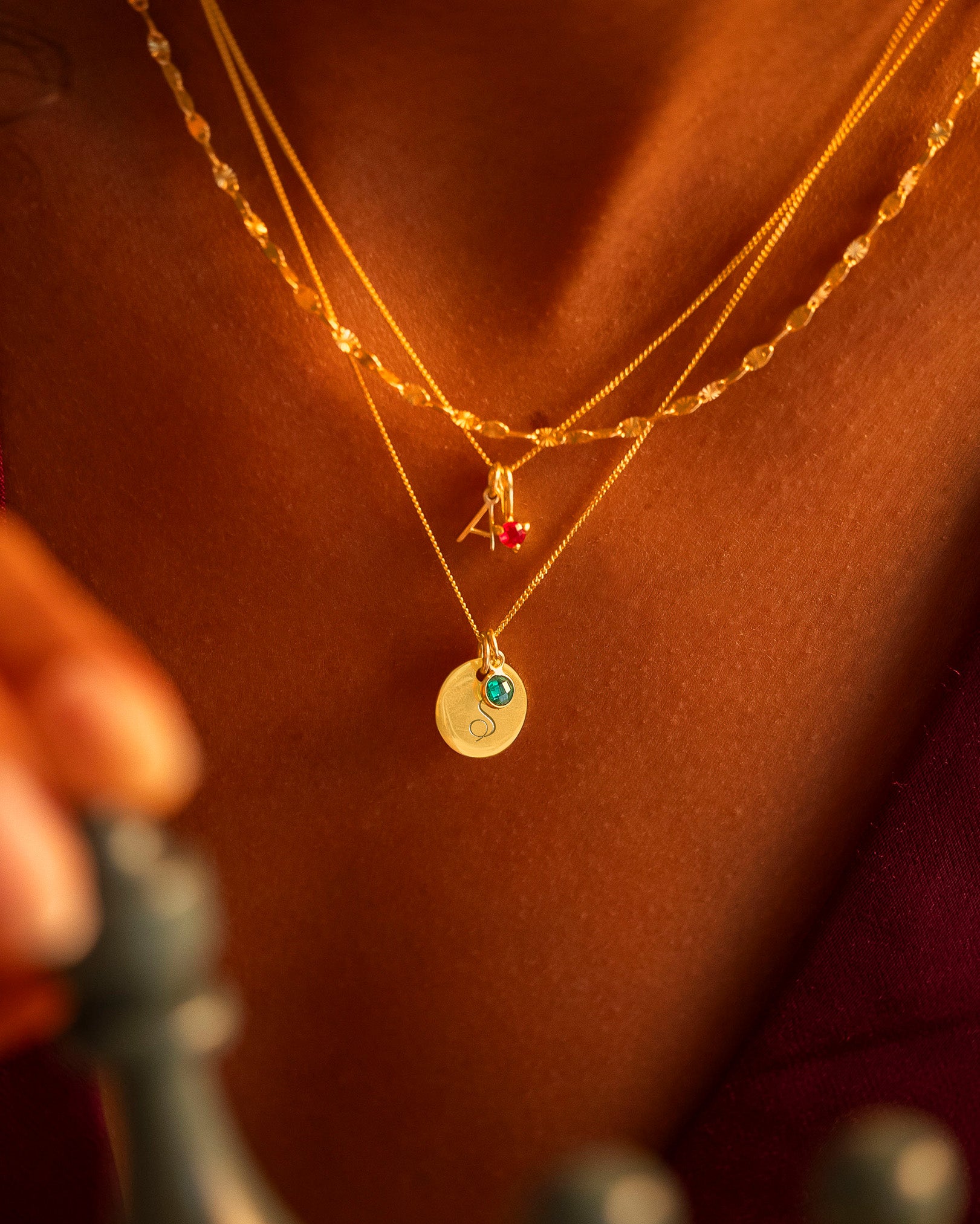 Close-up of a person wearing multiple gold necklaces with pendants.