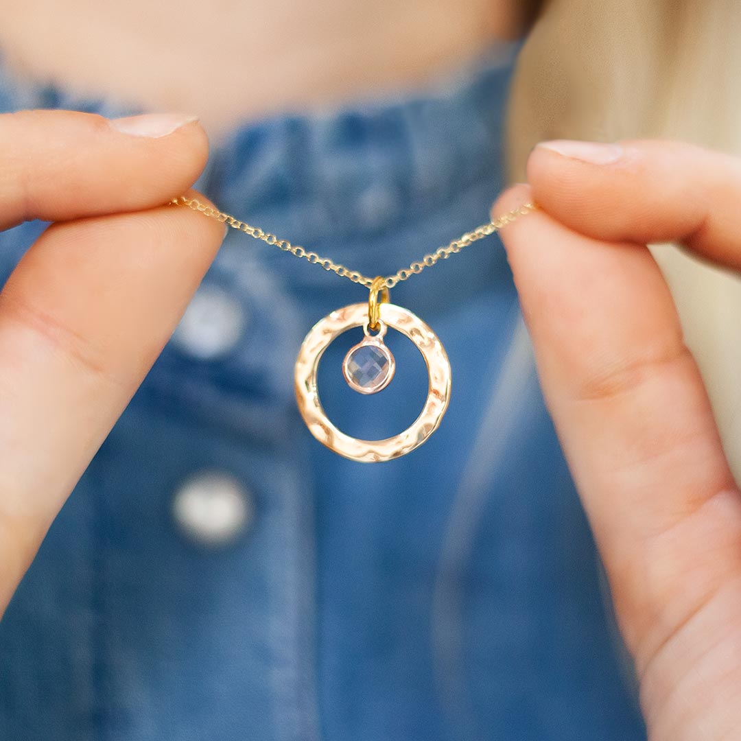 Model holding a Hammered Halo Necklace with Chosen Birthstone in Gold